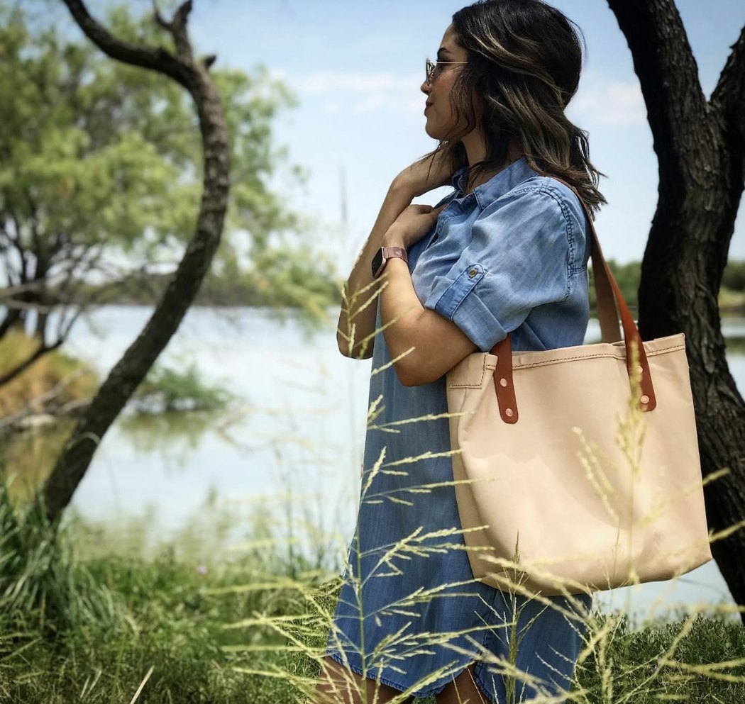 Frank's wife carrying a leather tote he made, by the lake